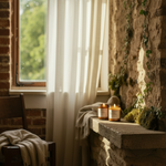 Candlelit scene with candles on a stone ledge by a window with white curtains.